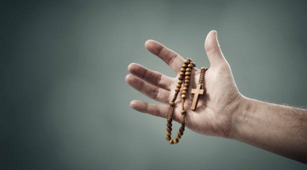 rosary beads and crucifix cross in hand background - praying human hand worshipper wood imagens e fotografias de stock
