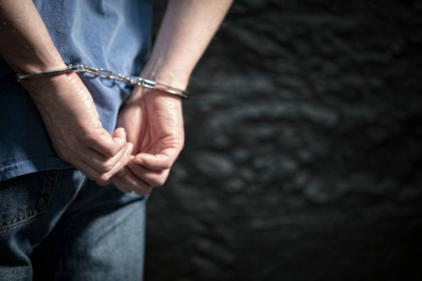 Criminal in handcuffs Arrested man in handcuffs with handcuffed hands behind back arrest photos stock pictures, royalty-free photos & images