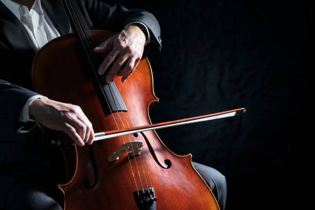 cello player o violonchelista actuando en un fondo de orquesta - chello fotografías e imágenes de stock