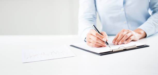 Woman's hands writing on sheet in a clipboard with a pen Woman's hands writing on sheet in a clipboard with a pen. Hands of businesswoman working with documents. tabs ring binder office isolated stock pictures, royalty-free photos & images