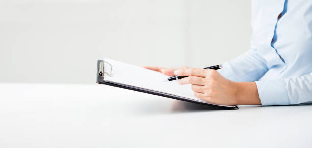 istock Woman's hands writing on sheet in a clipboard with a pen 1207760685