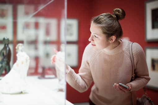 Young woman visitor using  phone  in the historical museum