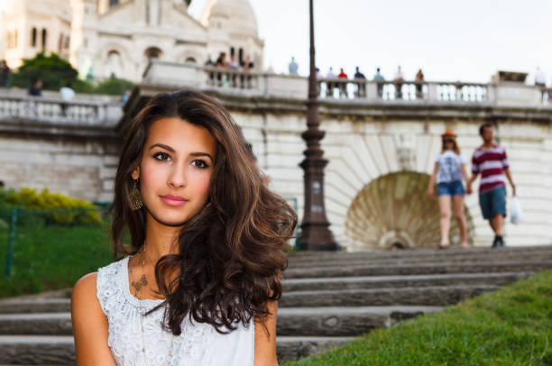 Young stylish woman with long hair leaning against a stone column at Palais Royal in Paris, France, enjoying peaceful moment.