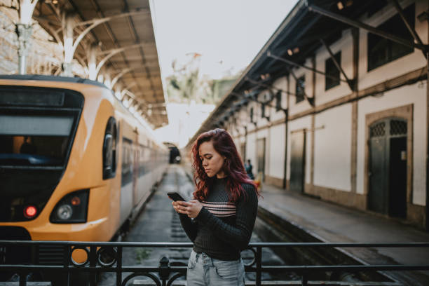 istock Young woman using phone inside a railroad station 1207784401