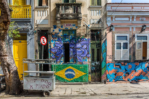 Rio de Janeiro, Brazil - July 3rd, 2016: An urban street with a downtown grungy feel in the Lapa neighbourhood in central Rio de Janeiro with an empty hot dog stand next to the pavement and graffiti on the walls in Brazil, South America