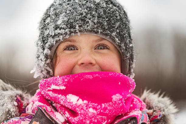 Close-up portrait of cute girl wearing knit hat. Adorable little female is smiling outdoors. She is with gray eyes.