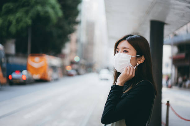 istock Young Asian woman wearing a protective face mask while waiting for public transportation in the city 1207793545