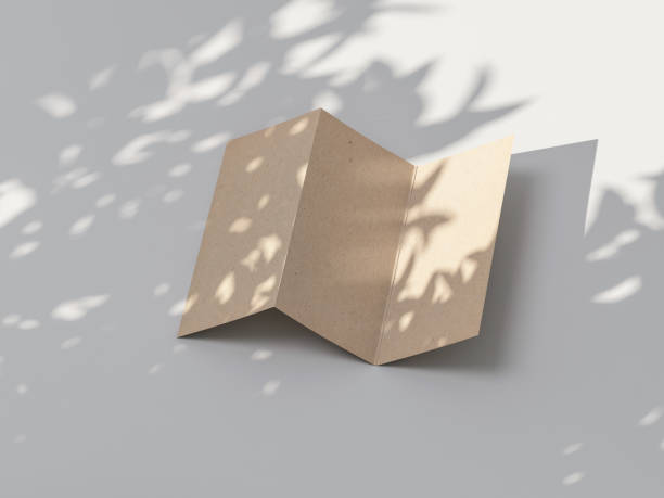 istock Kraft paper three folded Leaflet invitation Mockup on white table outdoors 1207796597