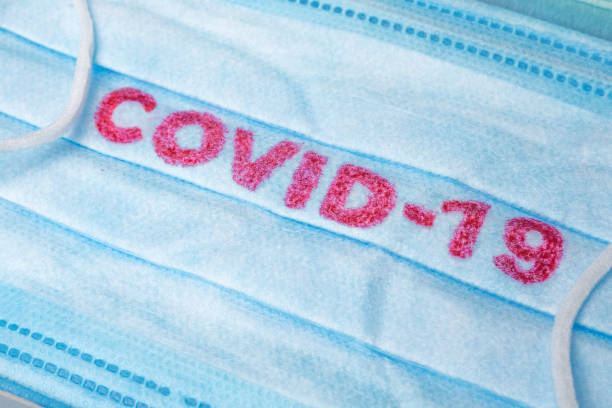 blue medical disposable face mask with covid-19 printed on it. covid-19 - wuhan novel coronavirus pneumonia gets official name from who: covid-19. disposable breath filter face mask with earloop - china covid imagens e fotografias de stock
