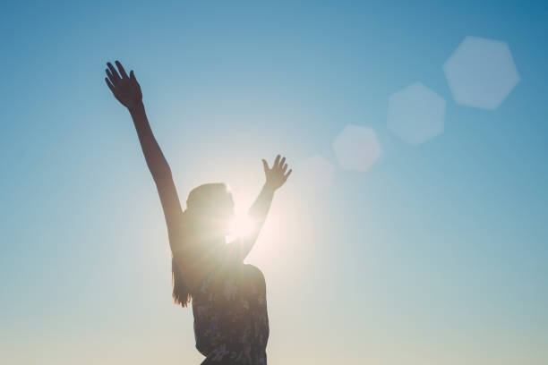 Silhouette of a girl with arms wide spread outdoors Silhouette of a girl with arms wide spread, the sun, rays and sky background hand extended stock pictures, royalty-free photos & images