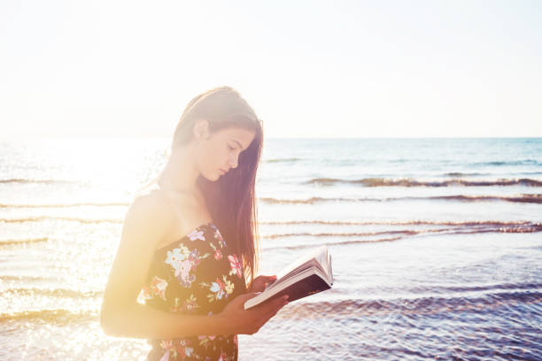 istock Girl in rays of sunlight reads book 1207798857
