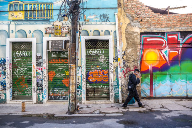 hombre fumando mientras camina frente a edificios de graffiti en el barrio de lapa de río de janeiro, brasil - graffiti paintings men walking fotografías e imágenes de stock