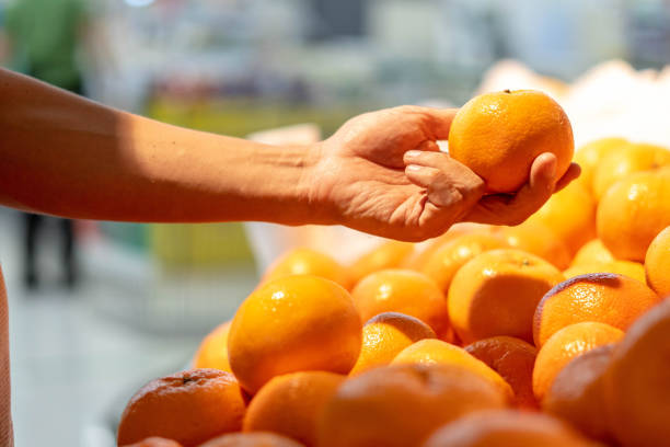 istock Hands holding oranges  in the supermarket. 1207801084
