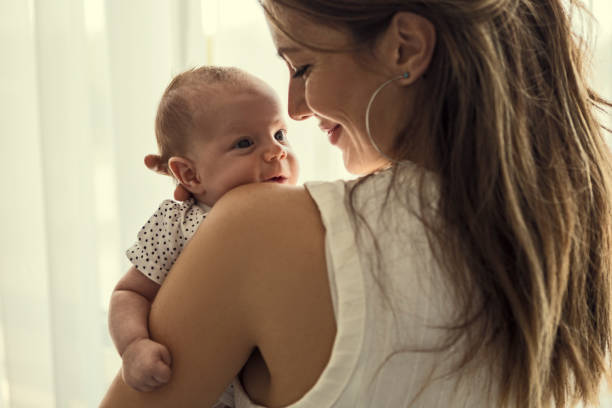 istock Beautiful mother with her baby on a shoulder smiling 1207801140