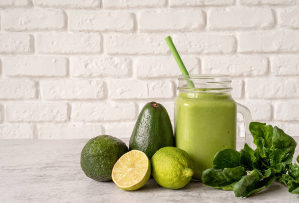 istock Avocado and spinach smoothie in mason jar front view on white brick wall background 1207805749