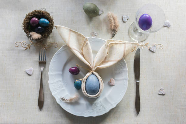 istock Easter festive spring table setting decoration, bunny ears shaped napkins, dyed eggs in nest, selective focus 1207807190