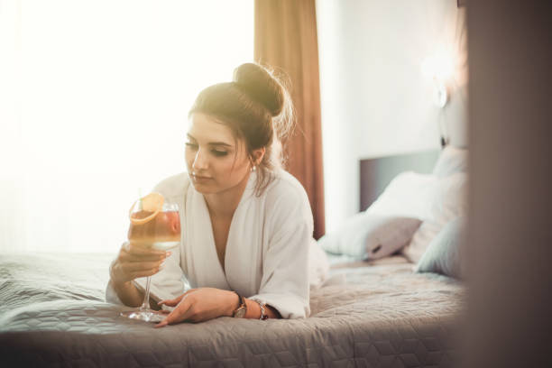 istock A young woman in a bathrobe enjoys bed and drinks a cocktail 1207810077