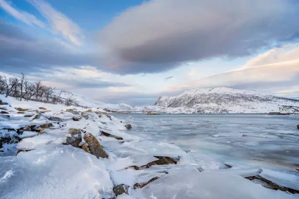 icy winterlandscape with dramatic sky on Kvaloeya Island near Tromsoe in northern Norway, landscape photography