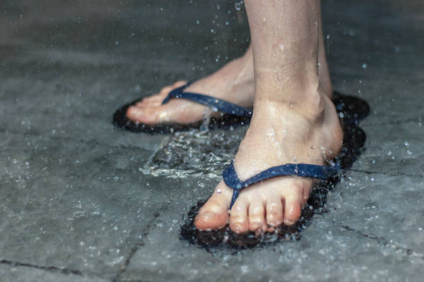 Flip flops on the feet of a person washing in the shower. Close up. stock photo