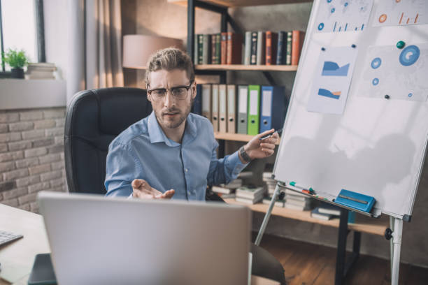 istock Young bearded man in eyeglasses making presentation online 1207816173