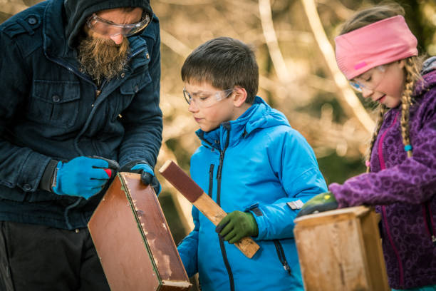 istock Teacher instructing a boy how to sand a wooden box 1207817083