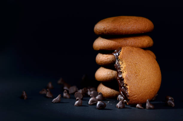 istock BISCUITS - Stack of delicious cream biscuits filled with chocolate cream on black background 1207820221