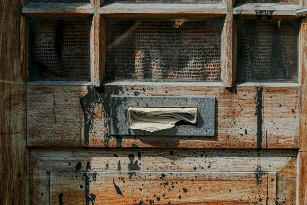 Newspaper in an old rustic mailbox in an old timber door splattered with black paint
