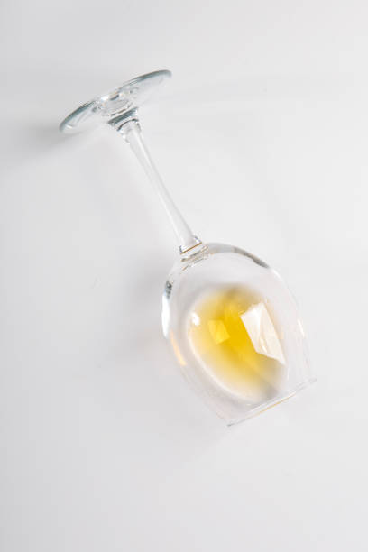 istock A glass of white wine lies on its side. White background 1207831003