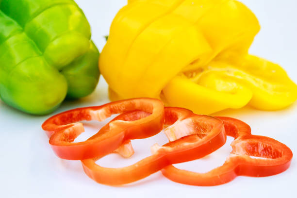 Red and yellow pepper sliced in thin slices on a white background