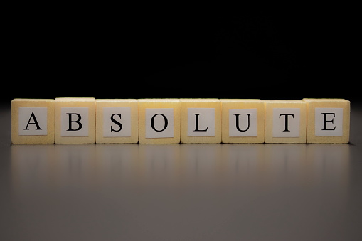 The word ABSOLUTE written on wooden cubes isolated on a black background