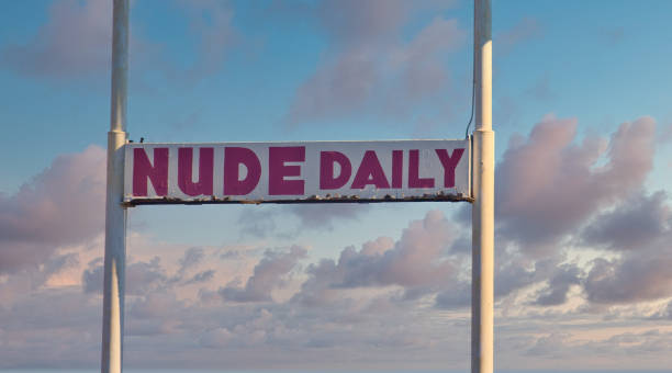 istock Old Rusty Nude Daily Sign on Dusk Sky 1207834363