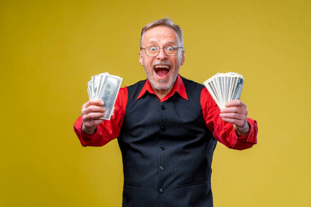 istock Happy elderly man showing two bunches of money. 1207836949