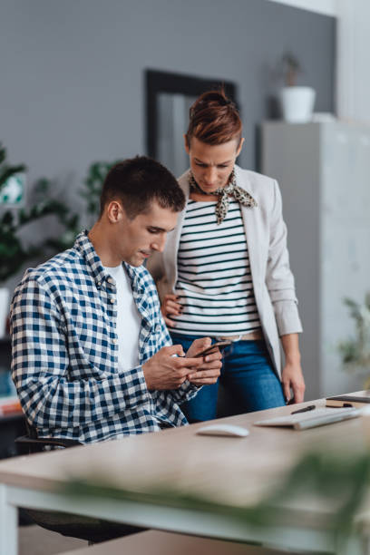istock Businessman helping his colleague with smart phone application 1207844837