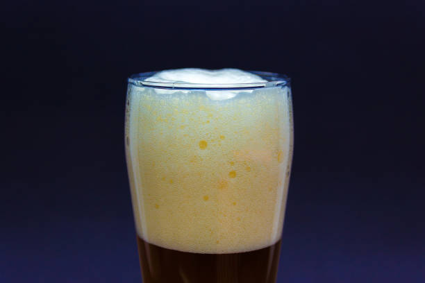 istock Fresh glass craft beer with white foam on top on a blue background. 1207846181