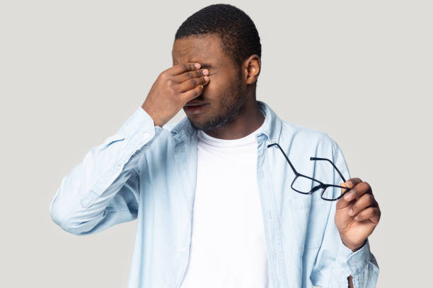 istock Exhausted unhealthy young african american man rubbing irritated eyes. 1207856395