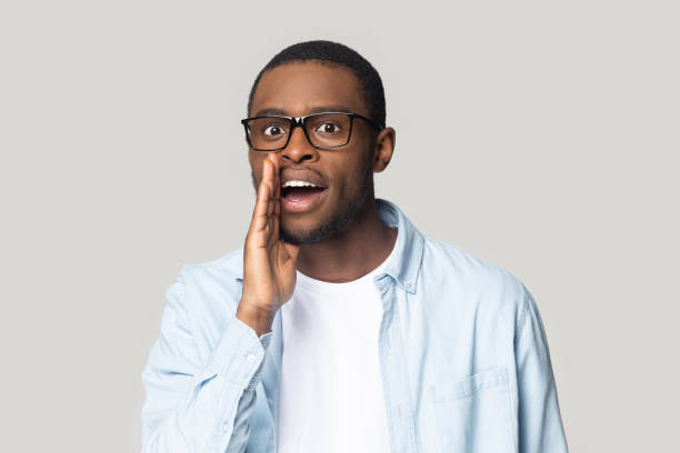 istock Young mysterious african american man telling secret, whispering gossip. 1207856408