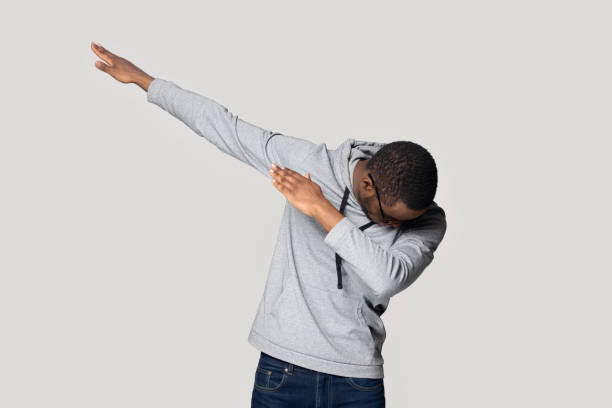 Happy young african american guy in sportswear making dab gesture. Happy young african american guy in sportswear performing show dance, making dab move gesture. Cheerful black millennial man presenting popular internet meme pose, isolated on grey studio background. dab dance photos stock pictures, royalty-free photos & images