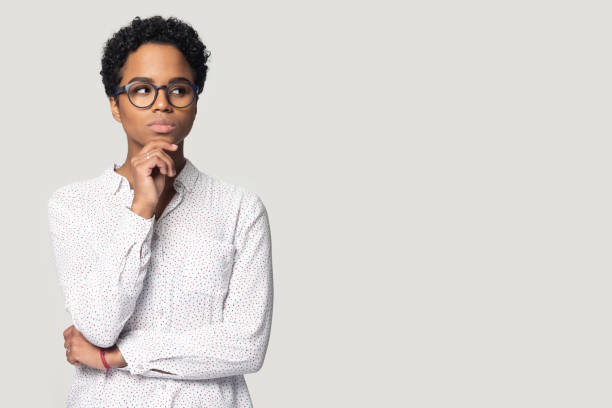 jonge peinzende etnische vrouw die terzijde op lege exemplaarruimte kijkt. - achterdocht fotos stockfoto's en -beelden