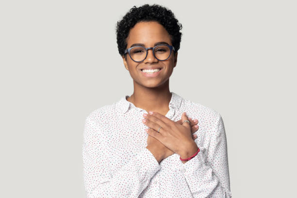 istock Thankful smiling black woman holding hands near heart on chest. 1207856496
