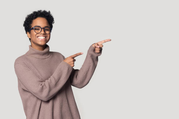 Happy smiling african american young woman pointing at copyspace.