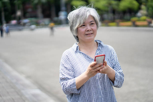 istock Senior woman using smart phone on street 1207856589