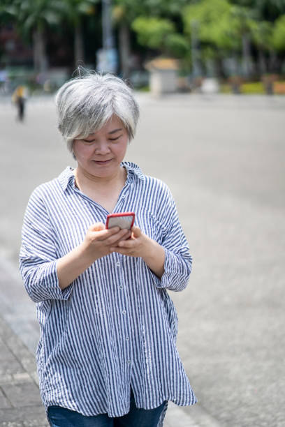 istock Senior chinese woman using smart phone on street 1207856593