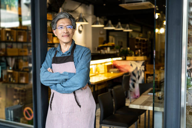 istock Mature man leaning on doorway of cafe 1207856605