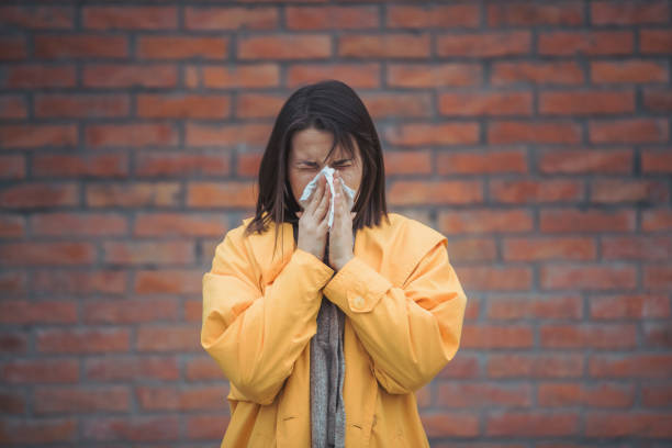 istock Sick young woman blowing her nose 1207856782