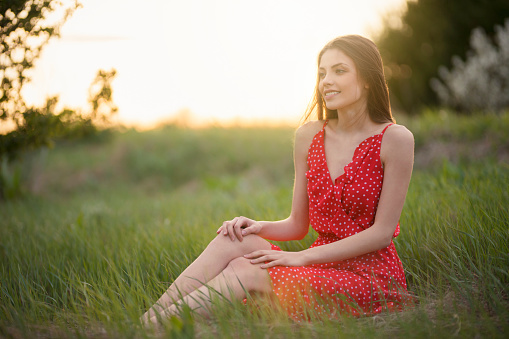 Spring portrait of a beautiful young woman sitting in the grass.