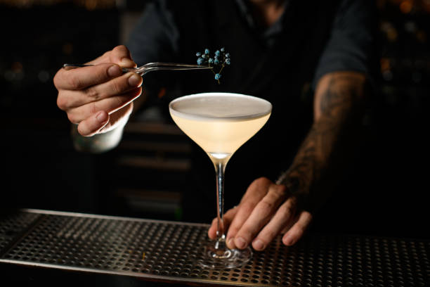 istock Professional bartender decorating a creamy alcoholic cocktail in the glass with a dried flower by tweezers 1207862039