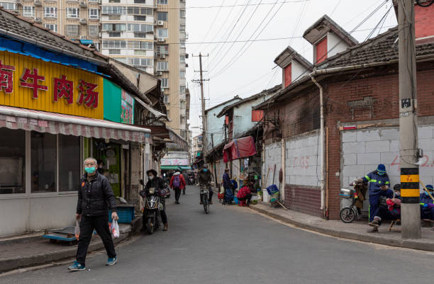 People wearing masks for protection against coronavirus at street market Shanghai, China - February 20, 2020: Street market on Wan'an Rd. at Jiangwanzhen with traditional old town buildings in Hongkou, Shanghai. People wear masks for protection from Covid-19 coronavirus. chinese slum stock pictures, royalty-free photos & images