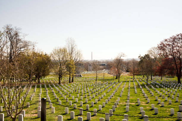 Gravestones at Arlington Cemetery Arlington, VA, USA. April 2, 2019. Rows and rows of gravestones at Arlington Cemetery with the obelisk in the far background. arlington cemetery in spring stock pictures, royalty-free photos & images