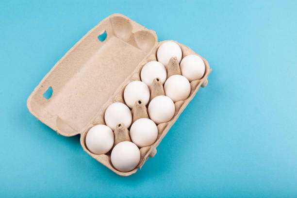 istock Egg Chicken eggs. Top view of an open gray box with white eggs. Isolated on a blue background. The concept of a healthy lifestyle, getting pure protein. Proper Breakfast. Preparing for Easter 1207878611