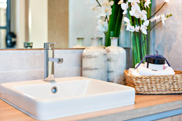 istock Silver taps and ceramic sink near perfume bottles with towels 1207883265